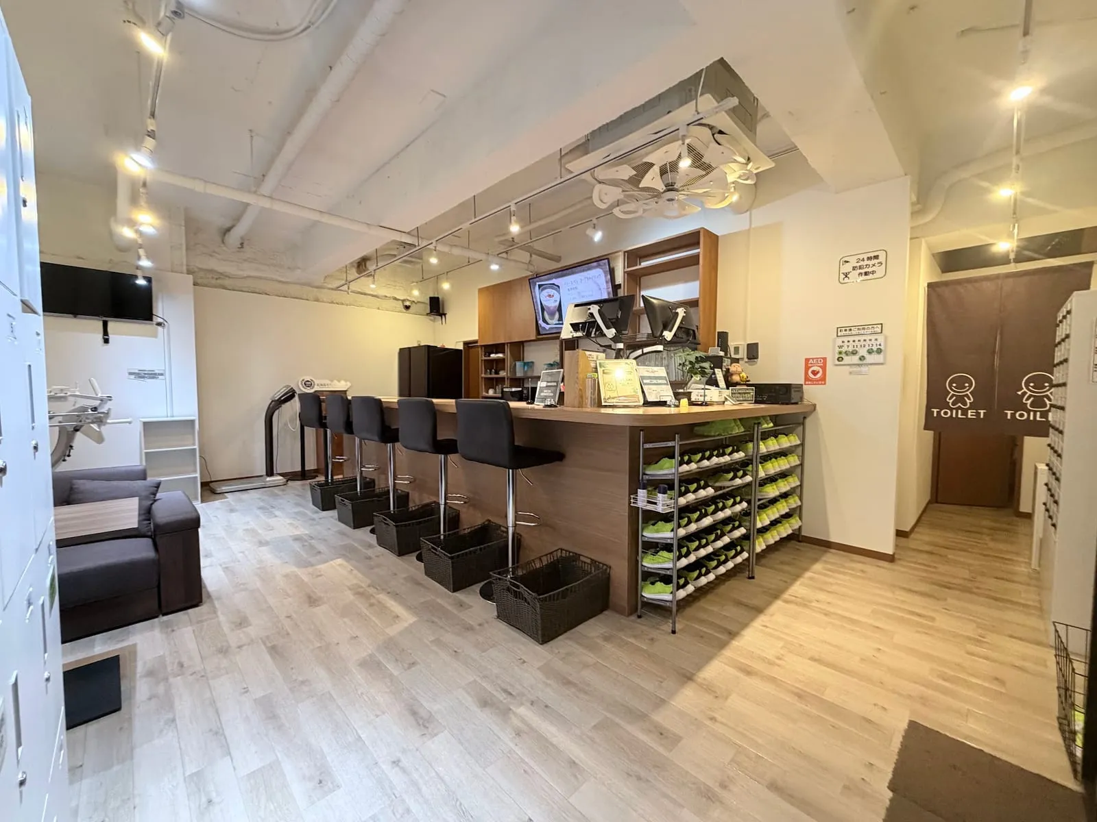 1階の受付カウンターとラウンジ全景。カウンター席、靴棚、トイレの案内