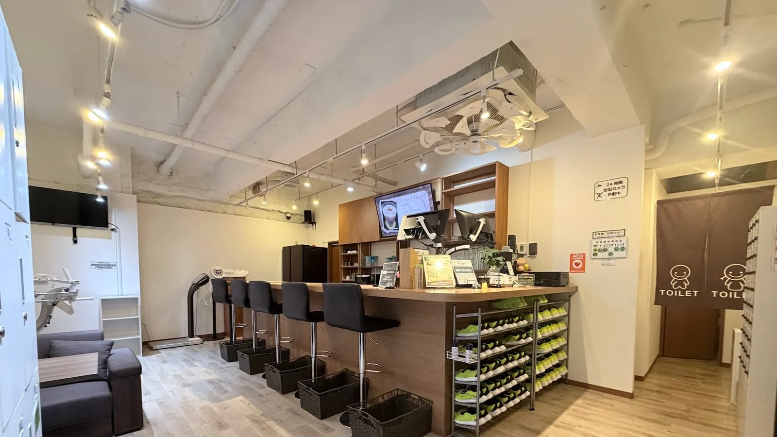 1階の受付カウンターとラウンジ全景。カウンター席、靴棚、トイレの案内
